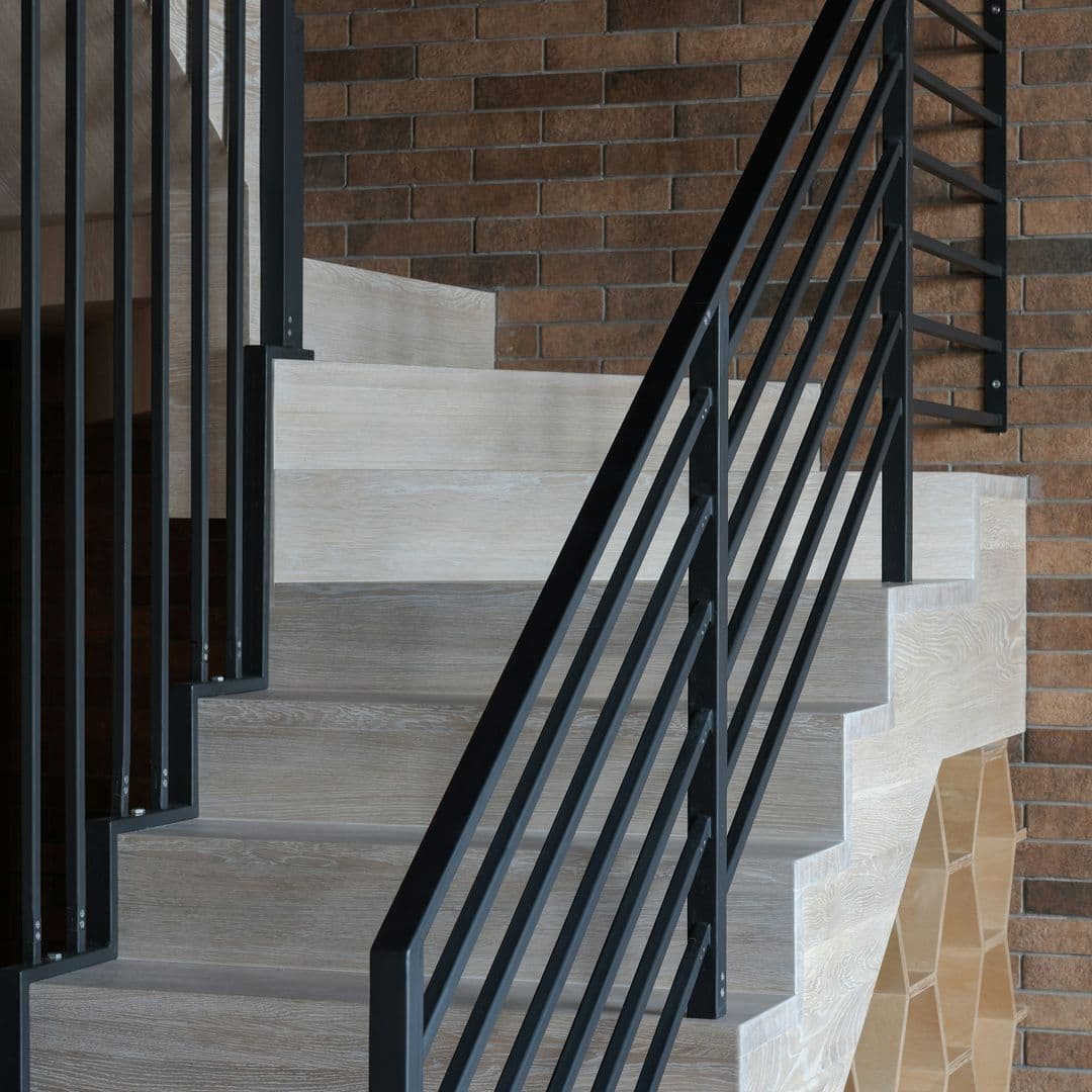 Graue Holztreppe mit schwarzem Handlauf