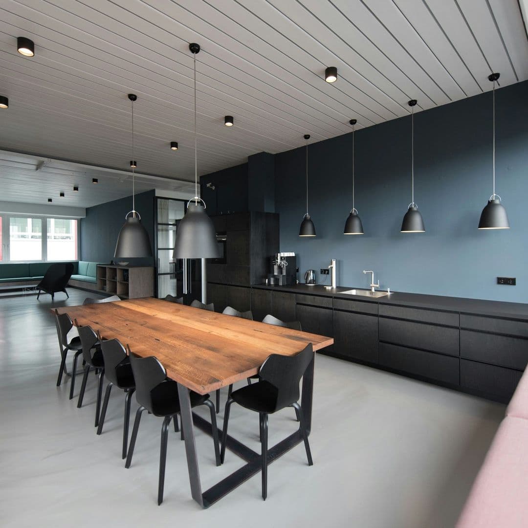 Pausenraum mit schwarzer Küche und langem Tisch